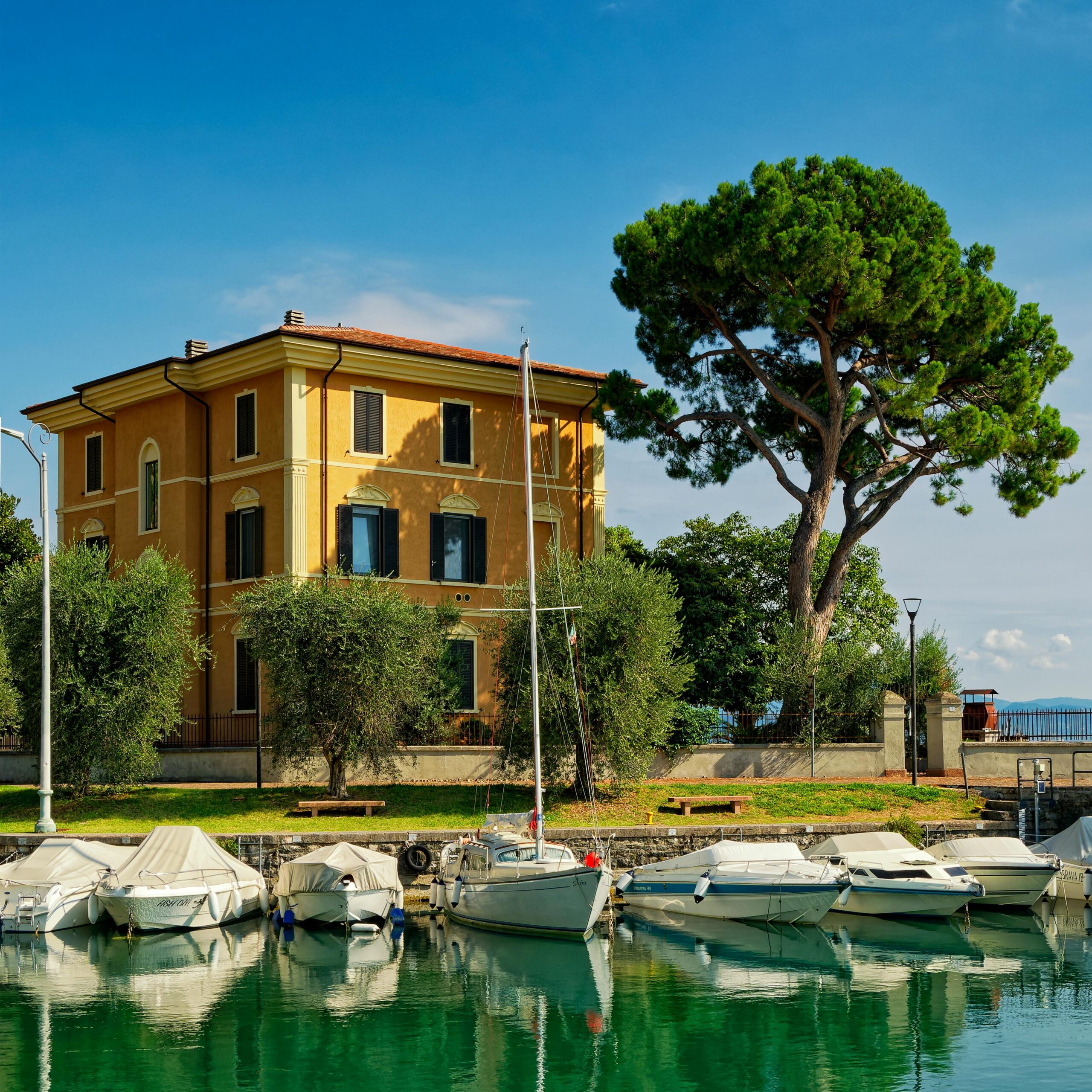 Charming villa with docked boats and lush greenery under a clear blue sky.