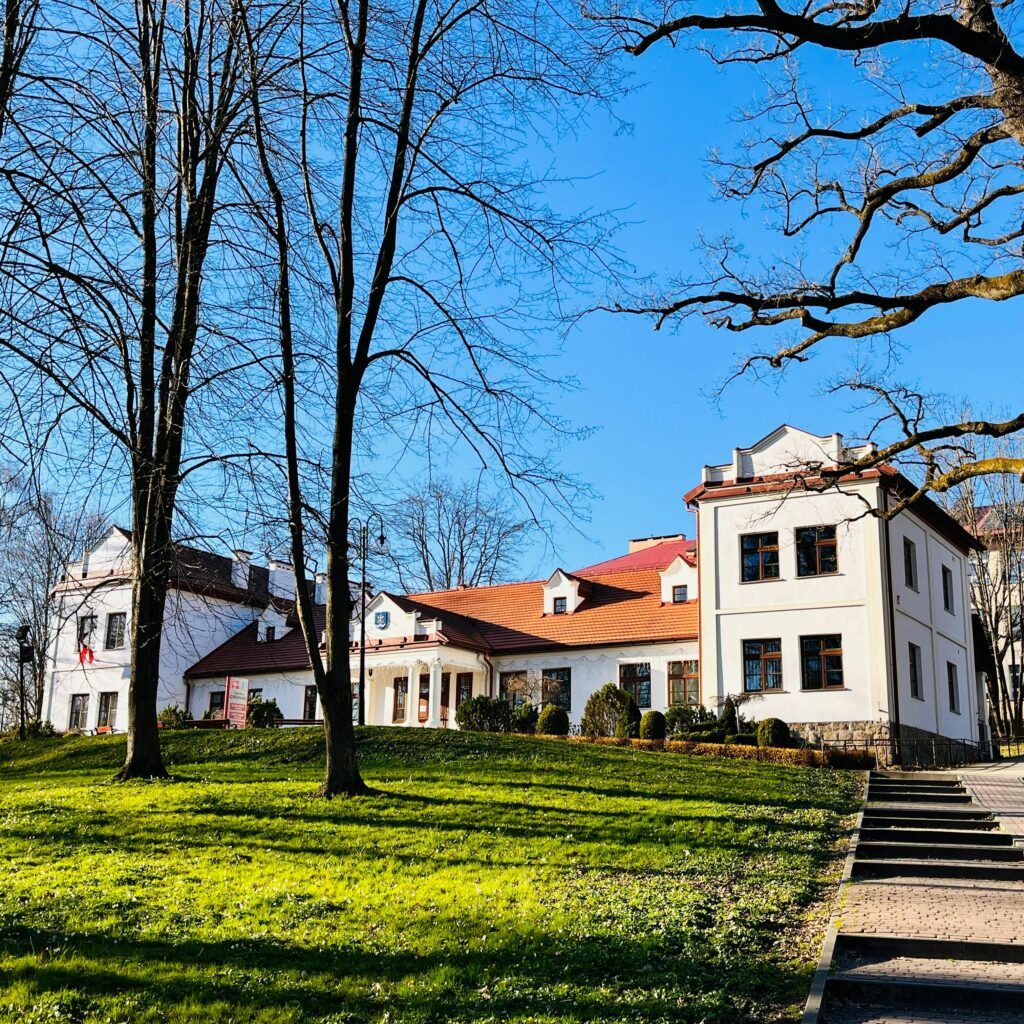 Beautiful manor house surrounded by leafless trees on a sunny spring day.
